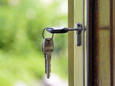 Image of open door with house keys sitting in lock