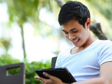 Young man sitting outdoors and working on a tablet