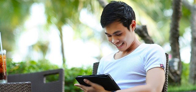 Young man sitting outdoors and working on a tablet