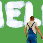 Man wearing overalls and holding paint roller standing in front of a green wall with the word HELP painted on it in white paint