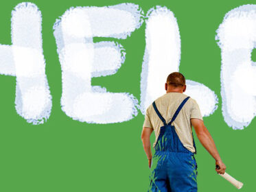 Man wearing overalls and holding paint roller standing in front of a green wall with the word HELP painted on it in white paint