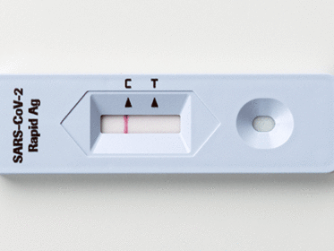 A saliva rapid antigen test sitting on a white background, the test is negative.