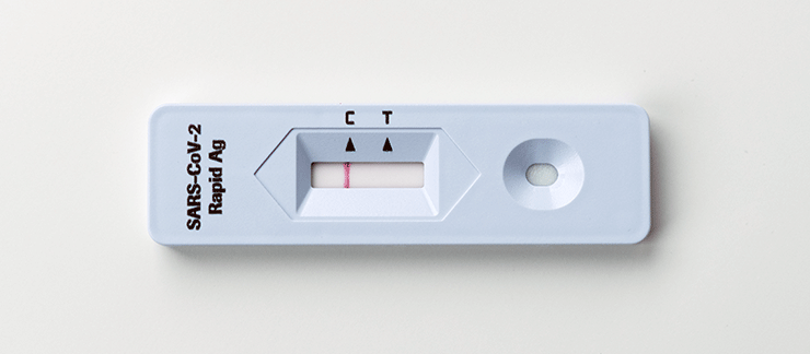 A saliva rapid antigen test sitting on a white background, the test is negative.